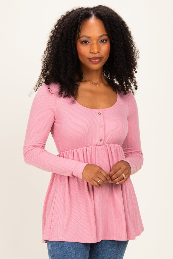 woman wearing a pink ribbed long sleeve top with a scoop neckline and button details, styled with a flared hem