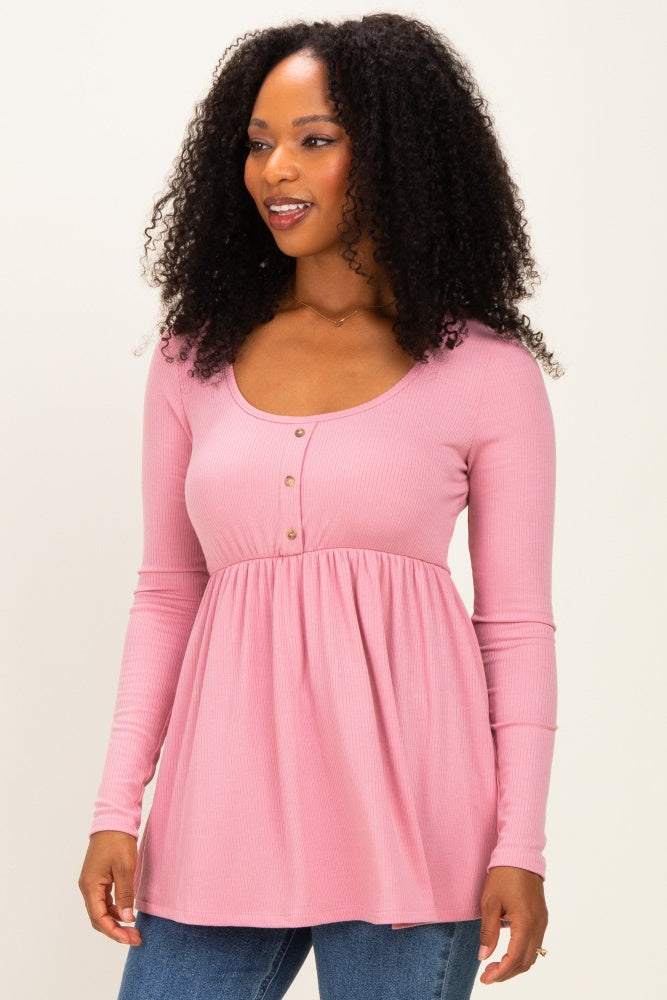 woman wearing a light pink long sleeve button-down top with a peplum style and dark blue jeans