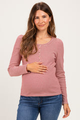 woman wearing a red and white striped maternity top with button details and holding her baby bump