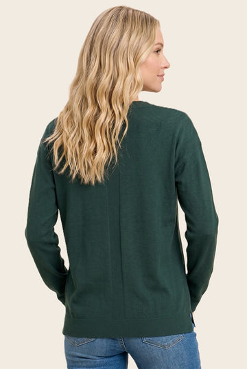 woman wearing a dark green sweater with a relaxed fit and ribbed details, shown from the back