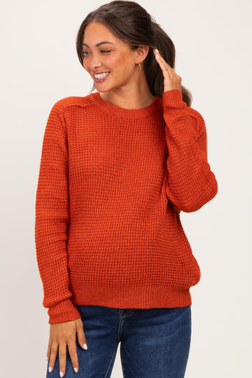 woman wearing an orange knit maternity sweater with long sleeves and a relaxed fit