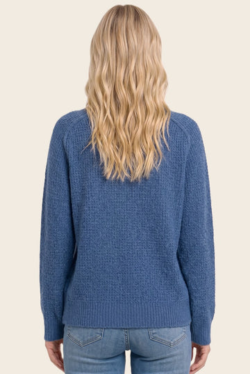 woman wearing a blue textured sweater with a relaxed fit, viewed from the back paired with denim jeans