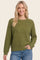 woman wearing a green textured knit sweater with a crew neckline and long sleeves, smiling