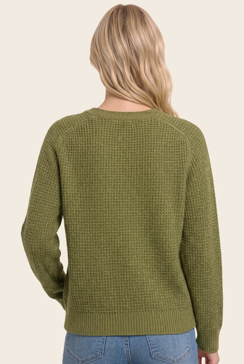 woman wearing a green textured knit sweater, shown from the back, styled with light blue jeans