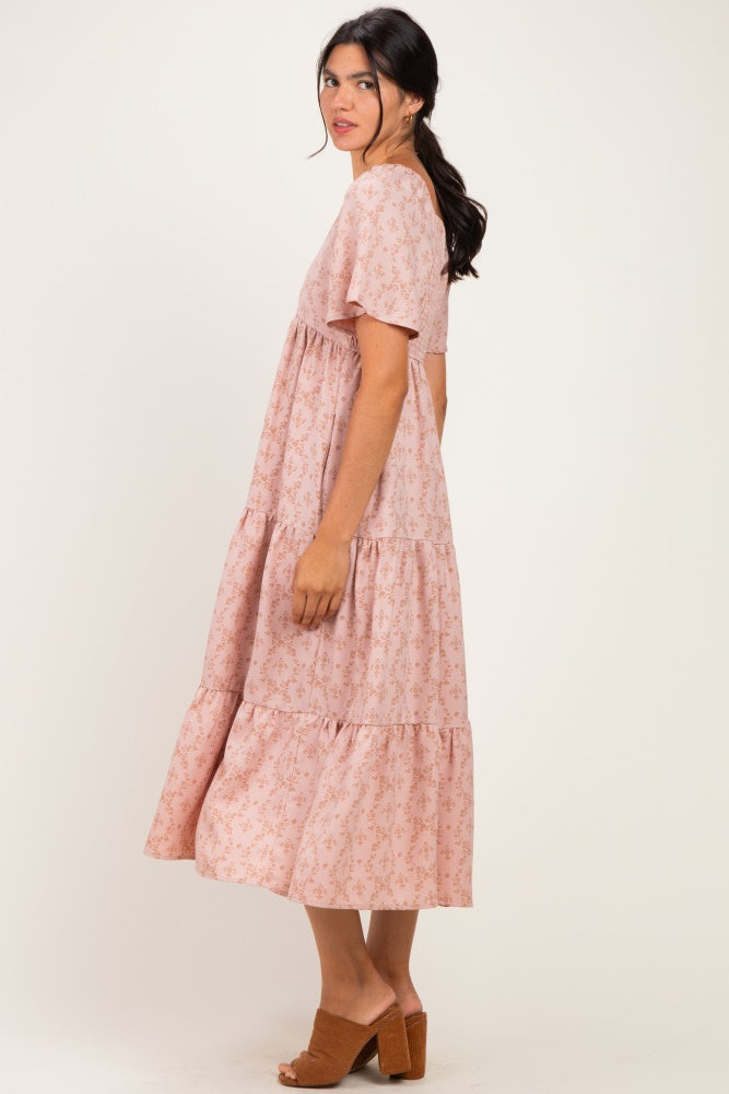 woman wearing a pink floral maxi dress with short sleeves and a tiered hem, standing sideways