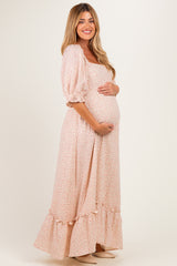 woman wearing a floral maternity maxi dress with puff sleeves and a ruffled hem, showcasing her baby bump