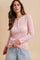 woman wearing a pink floral long sleeve henley top with button details and contrast cuffs, paired with light blue jeans