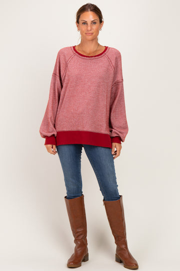 woman wearing a red and pink striped oversized sweater with dropped shoulders and blue jeans, paired with brown knee-high boots