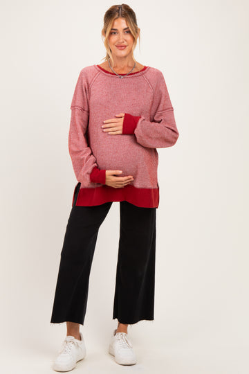woman wearing a red and white striped maternity sweater, holding her baby bump, paired with black wide-leg pants