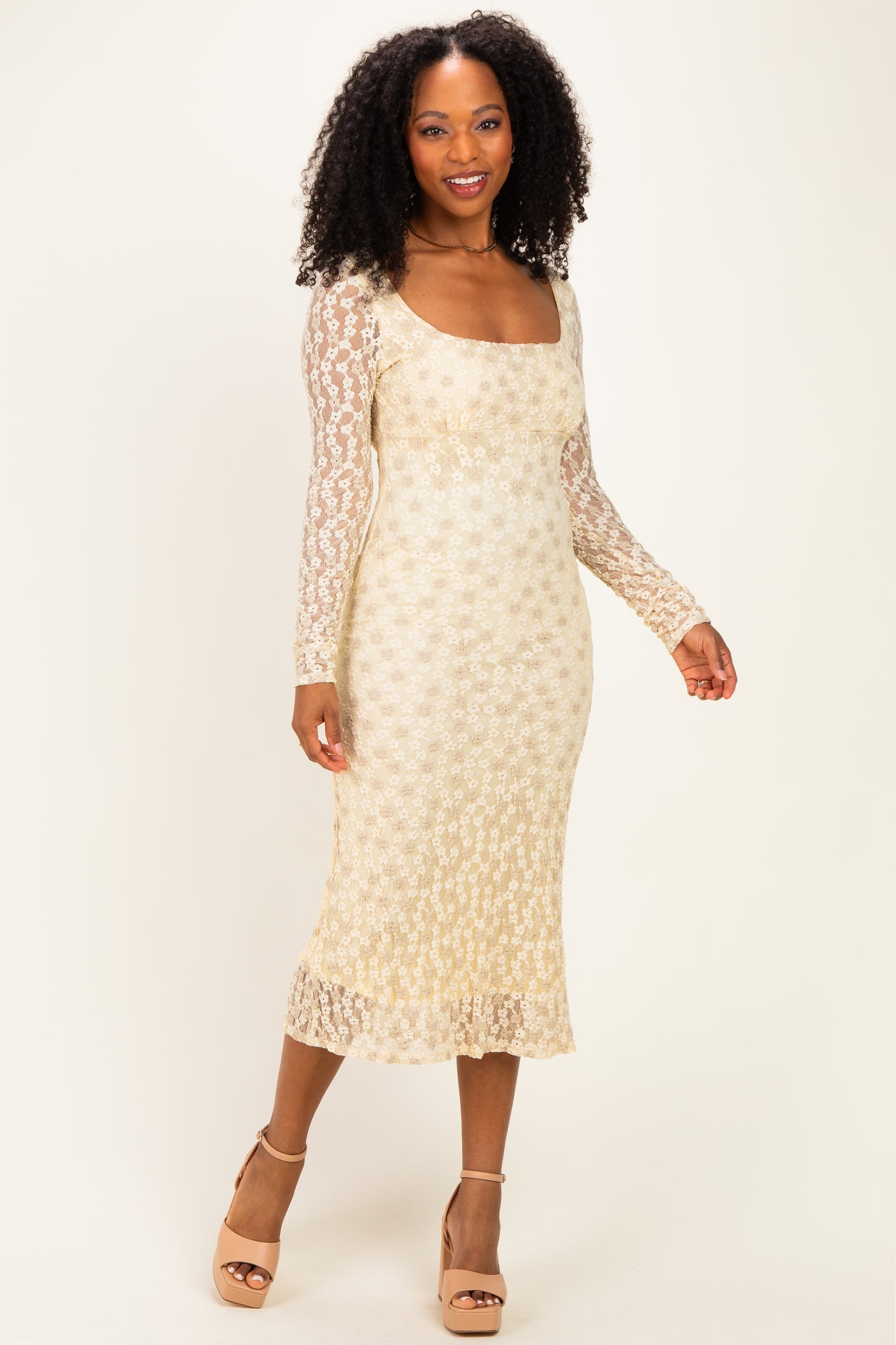 woman wearing a gold floral lace long sleeve midi dress with a square neckline and fitted silhouette