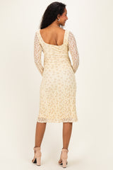 woman wearing a light beige lace maternity dress with long sleeves, showing a flattering back view