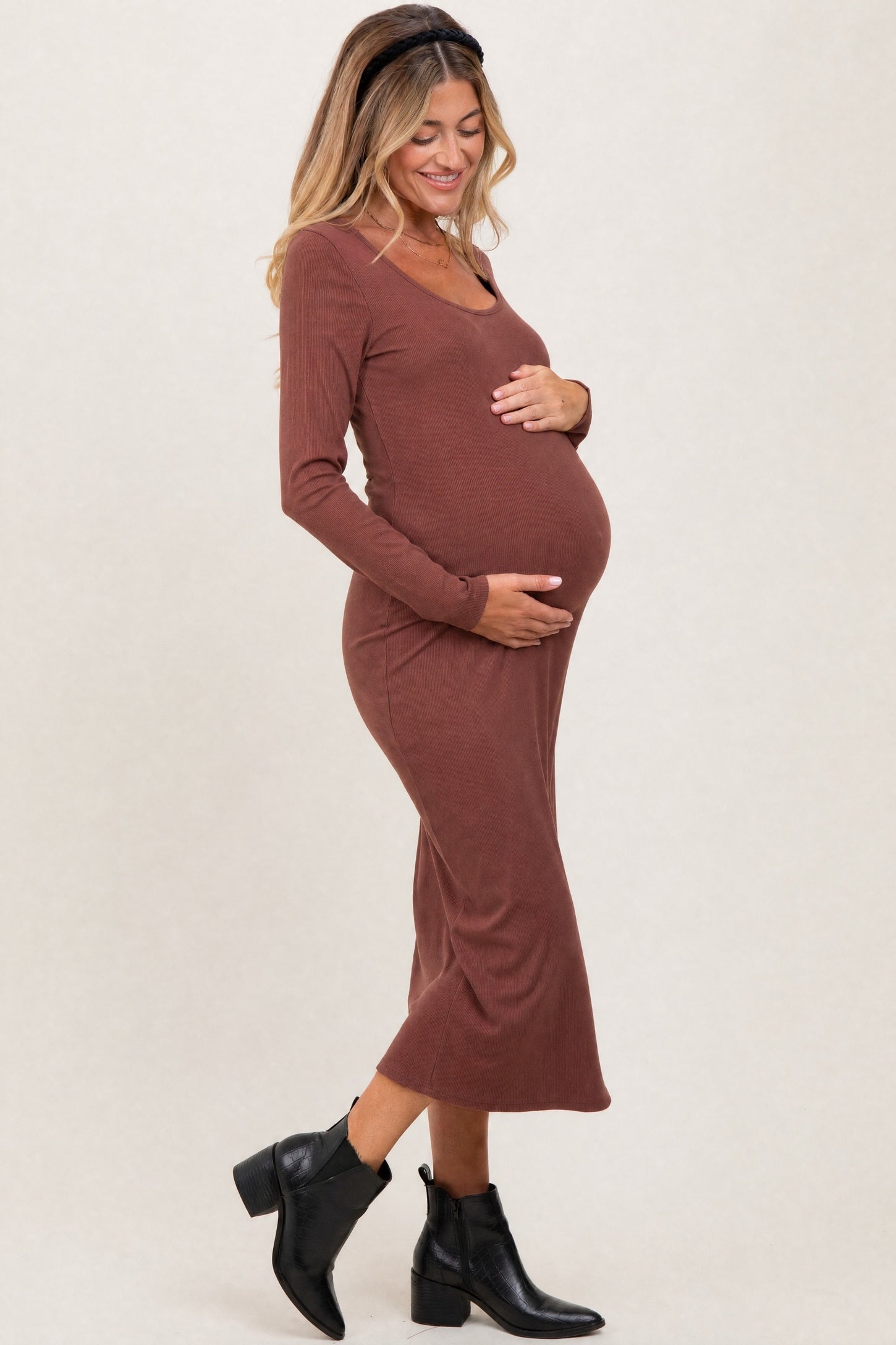 woman wearing a brown long sleeve maternity dress and holding her baby bump