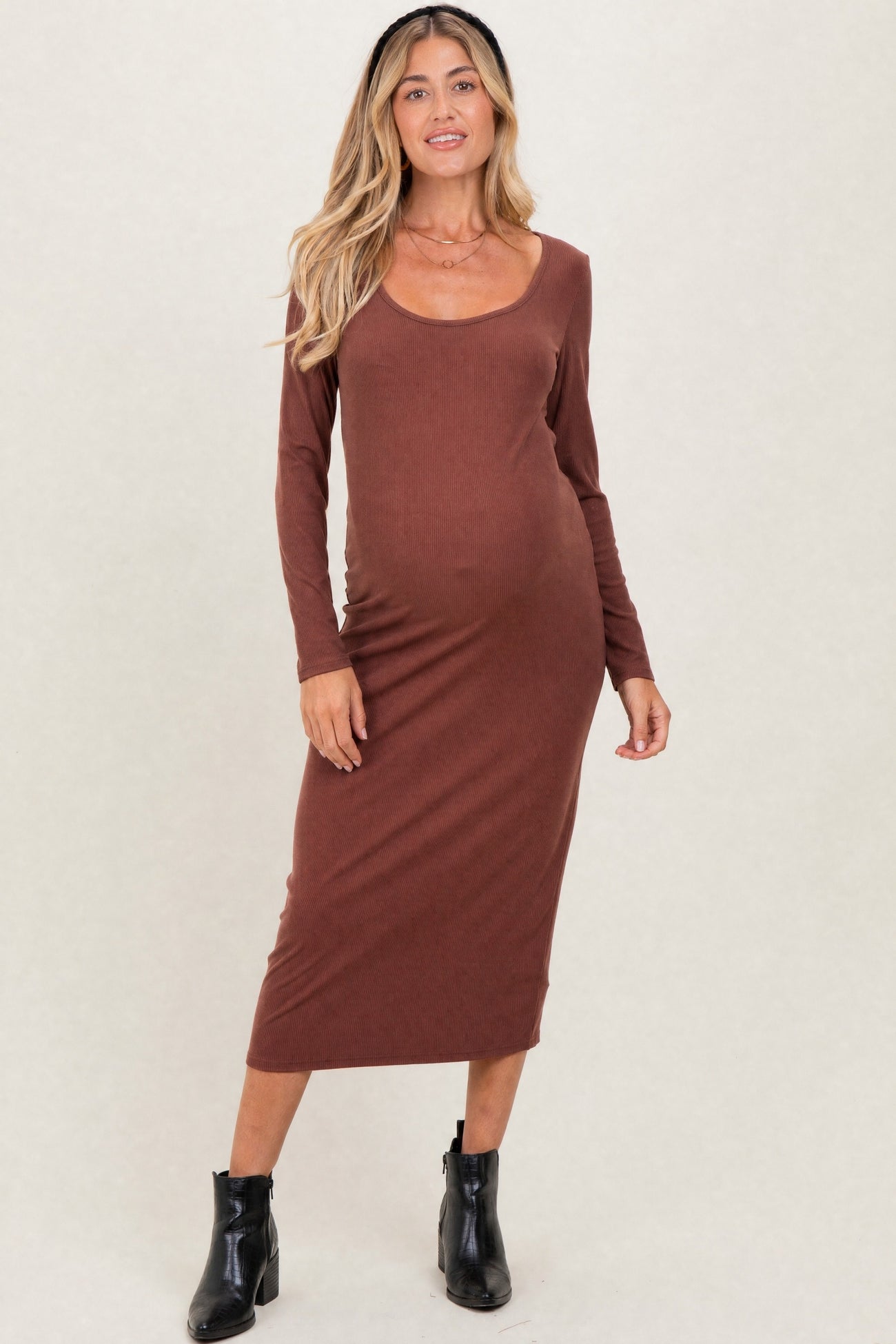 woman wearing a rust-colored long sleeve maternity dress, showcasing her baby bump