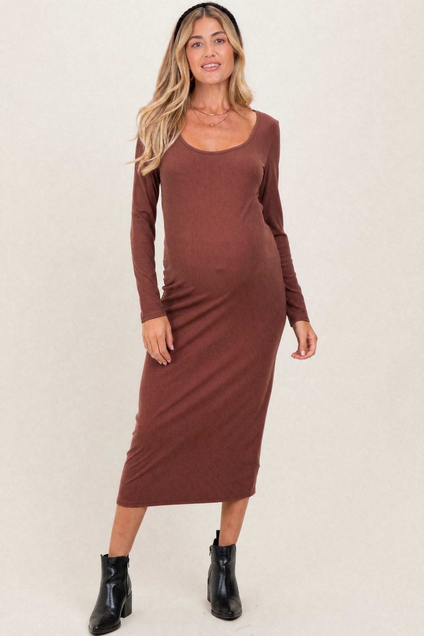 woman wearing a rust-colored long sleeve maternity dress, showcasing her baby bump