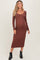 woman wearing a rust-colored long sleeve maternity dress, showcasing her baby bump