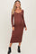 woman wearing a rust-colored long sleeve maternity dress, showcasing her baby bump