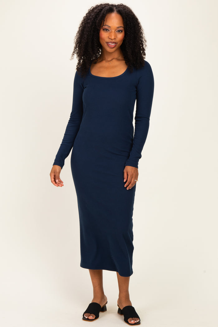 woman wearing a navy long sleeve ribbed dress with a scoop neckline and black slide sandals
