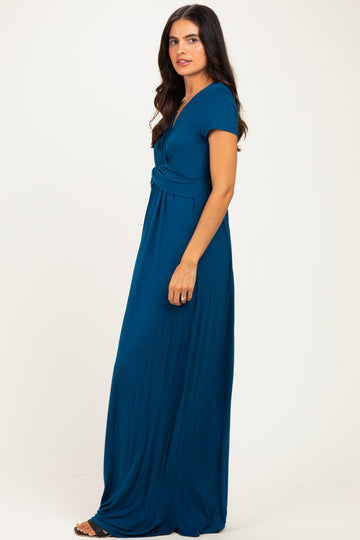 woman wearing a teal maxi dress with a twisted front detail and short sleeves