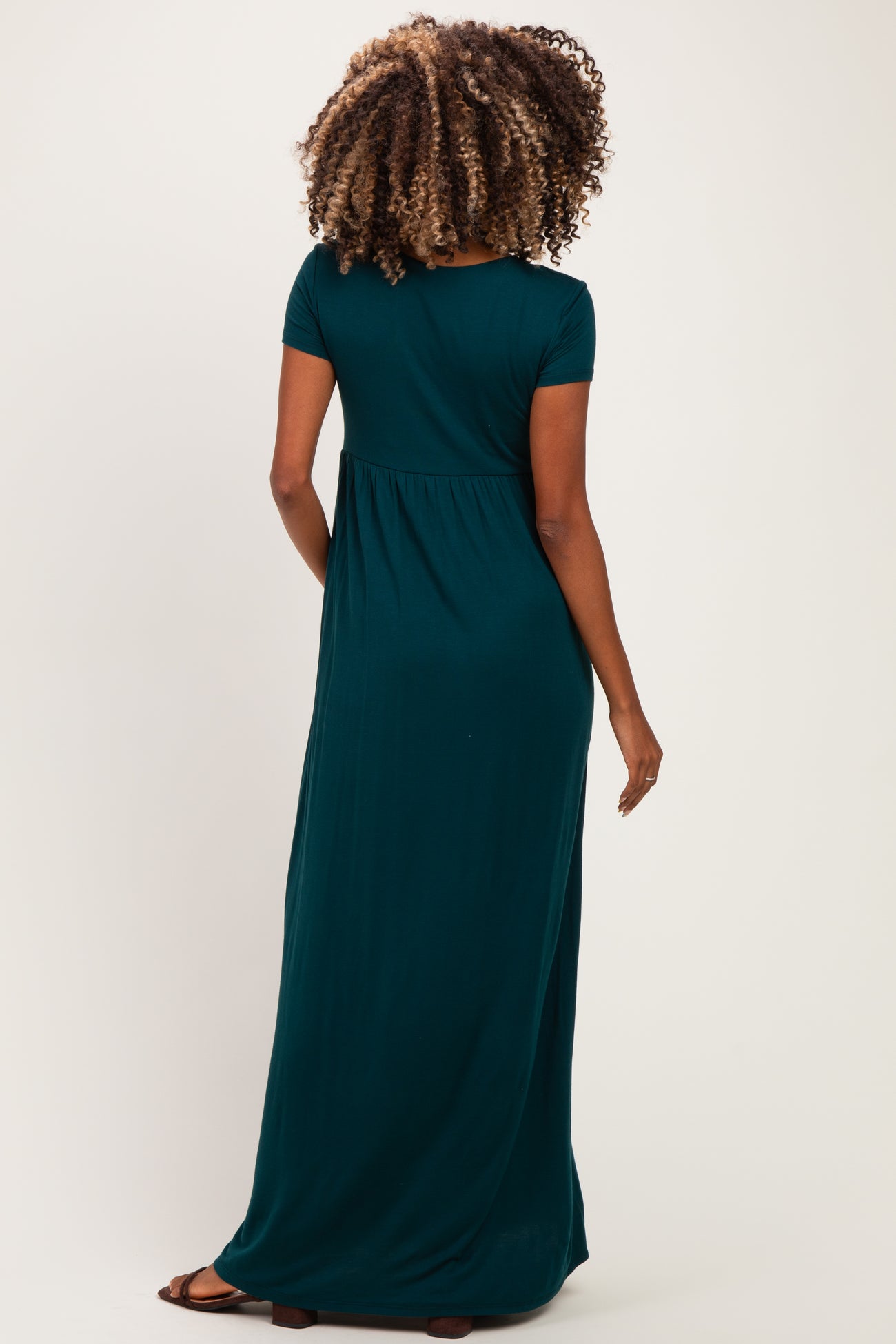 woman wearing a dark green maternity maxi dress with short sleeves and a relaxed fit, showcasing her baby bump