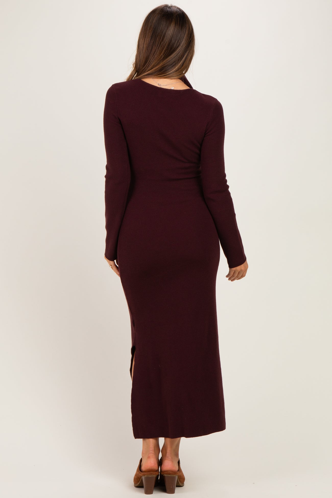 woman wearing a burgundy long sleeve ribbed maternity dress with a side slit, showing a smooth silhouette