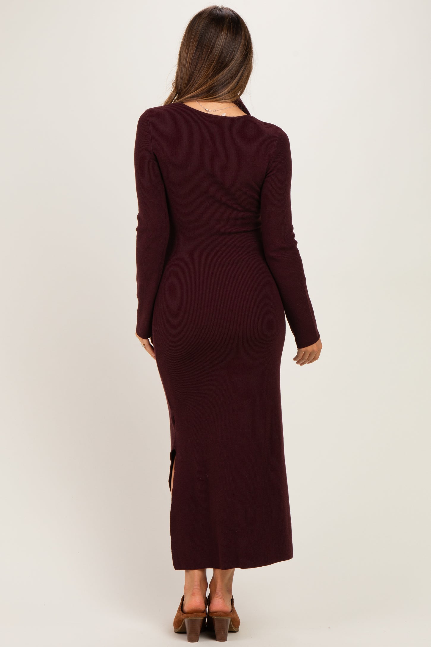 woman wearing a burgundy long sleeve ribbed maternity dress with a side slit, showing a smooth silhouette