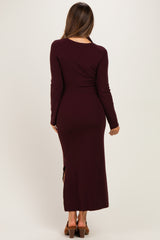 woman wearing a burgundy long sleeve ribbed maternity dress with a side slit, showing a smooth silhouette