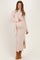 woman wearing a light pink ribbed maternity dress with a side slit and a long scarf, holding her baby bump