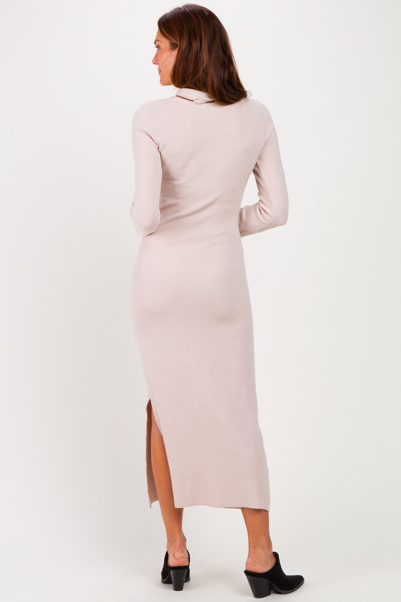 woman wearing a pale pink ribbed long sleeve midi dress with a side slit and open back