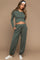 woman wearing a green maternity long sleeve top with a twist front and matching jogger pants, showing her baby bump