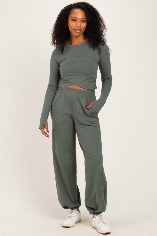 woman wearing a long sleeve olive green cropped top and matching wide-leg pants, paired with white sneakers