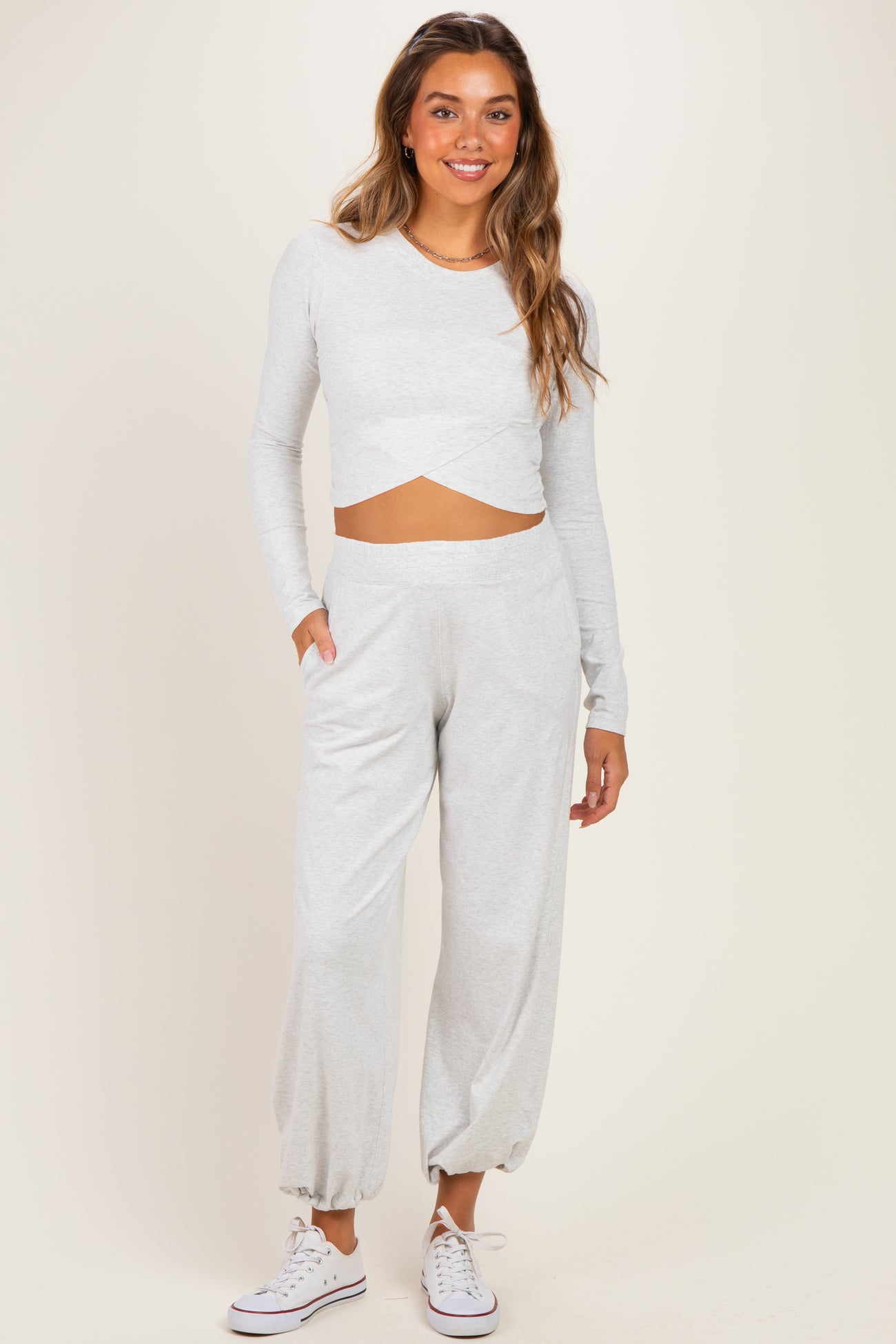 woman wearing a light gray long sleeve cropped maternity top and matching relaxed-fit maternity joggers