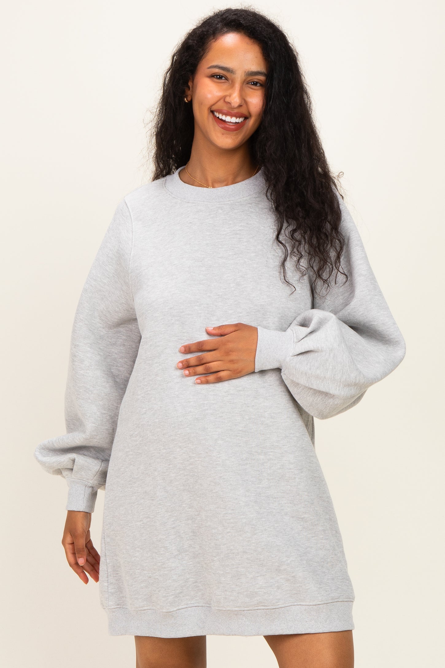 woman wearing a gray maternity sweatshirt dress with long balloon sleeves and holding her baby bump