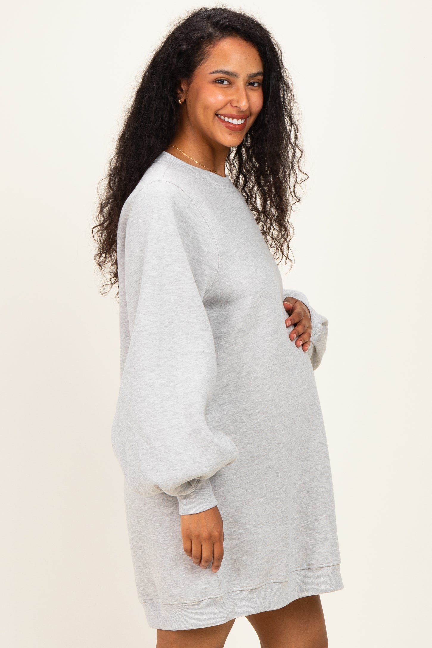 woman wearing a gray maternity sweatshirt dress with puff sleeves and holding her baby bump