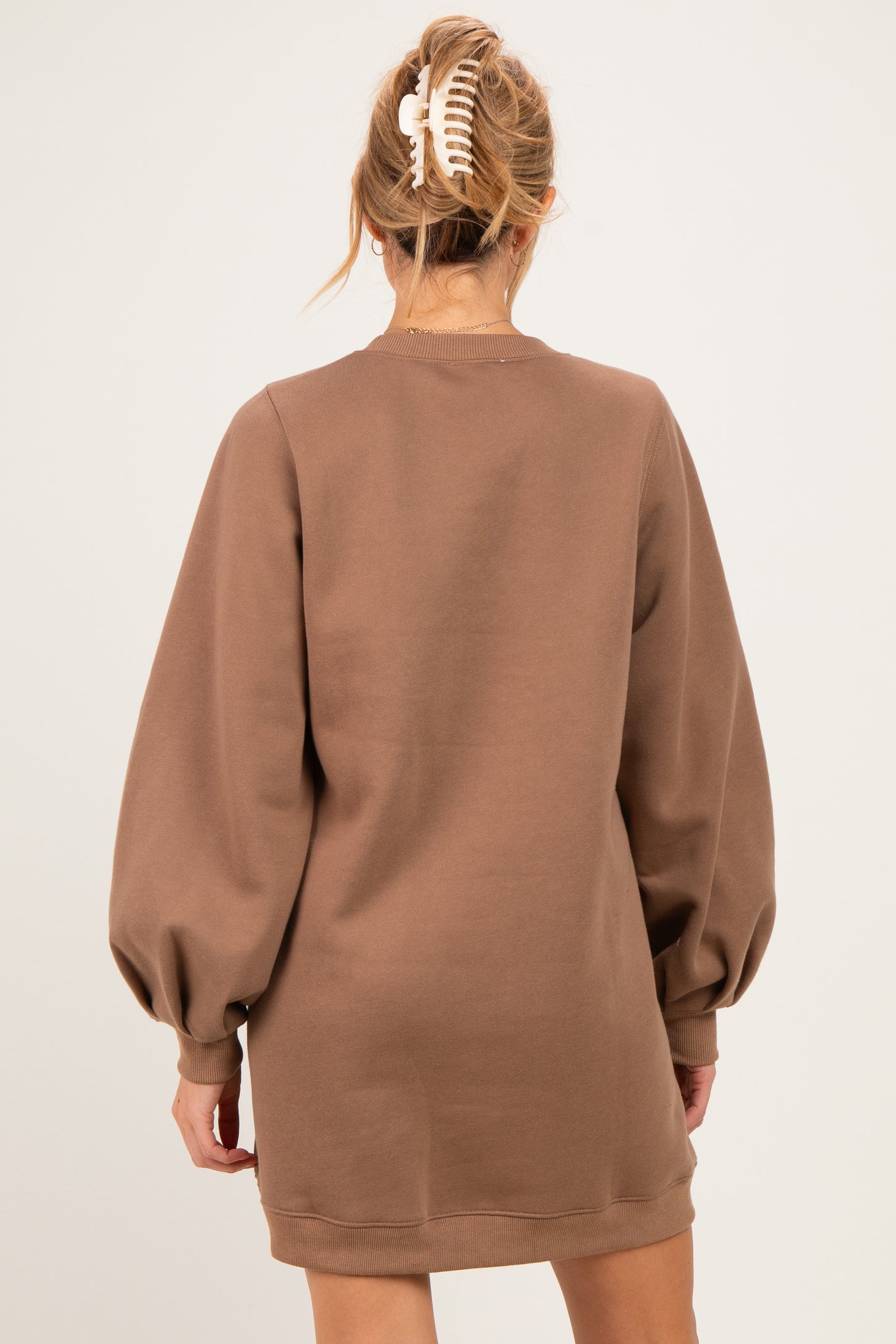 woman wearing a brown maternity sweatshirt dress with puffed sleeves, showing the back view