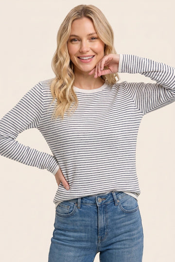 woman wearing a light gray and white striped long sleeve top with a relaxed fit and smiling at the camera