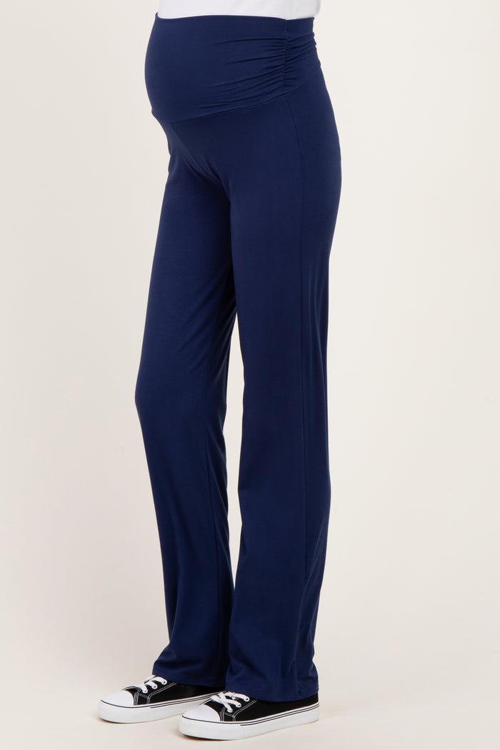 woman wearing navy blue maternity yoga pants with a ruched waistband and a visible baby bump