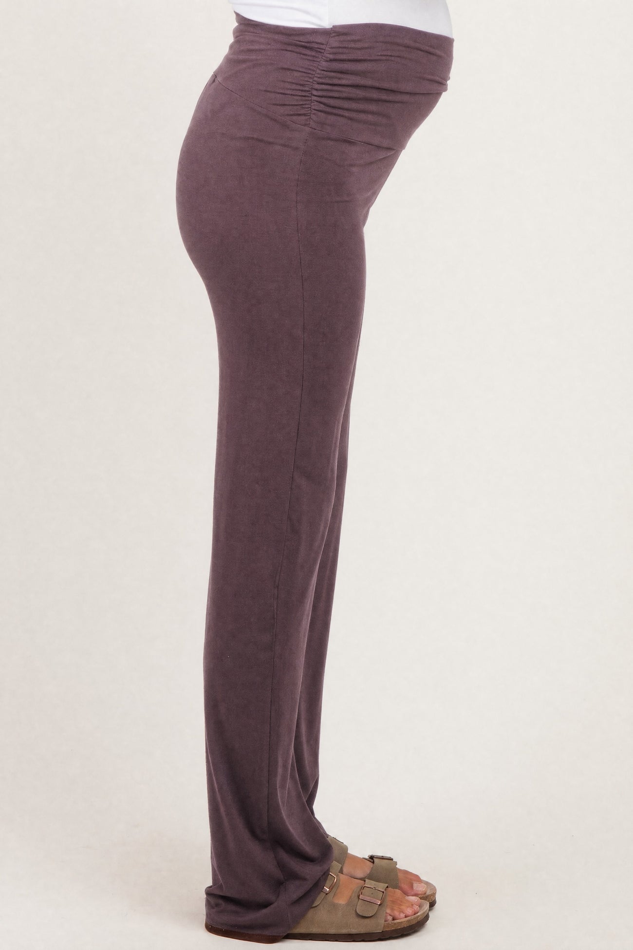 woman wearing a purple maternity pant with ruched details and a visible baby bump