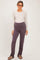 woman wearing a light beige long sleeve henley top and dark purple maternity pants with a ruched waistband