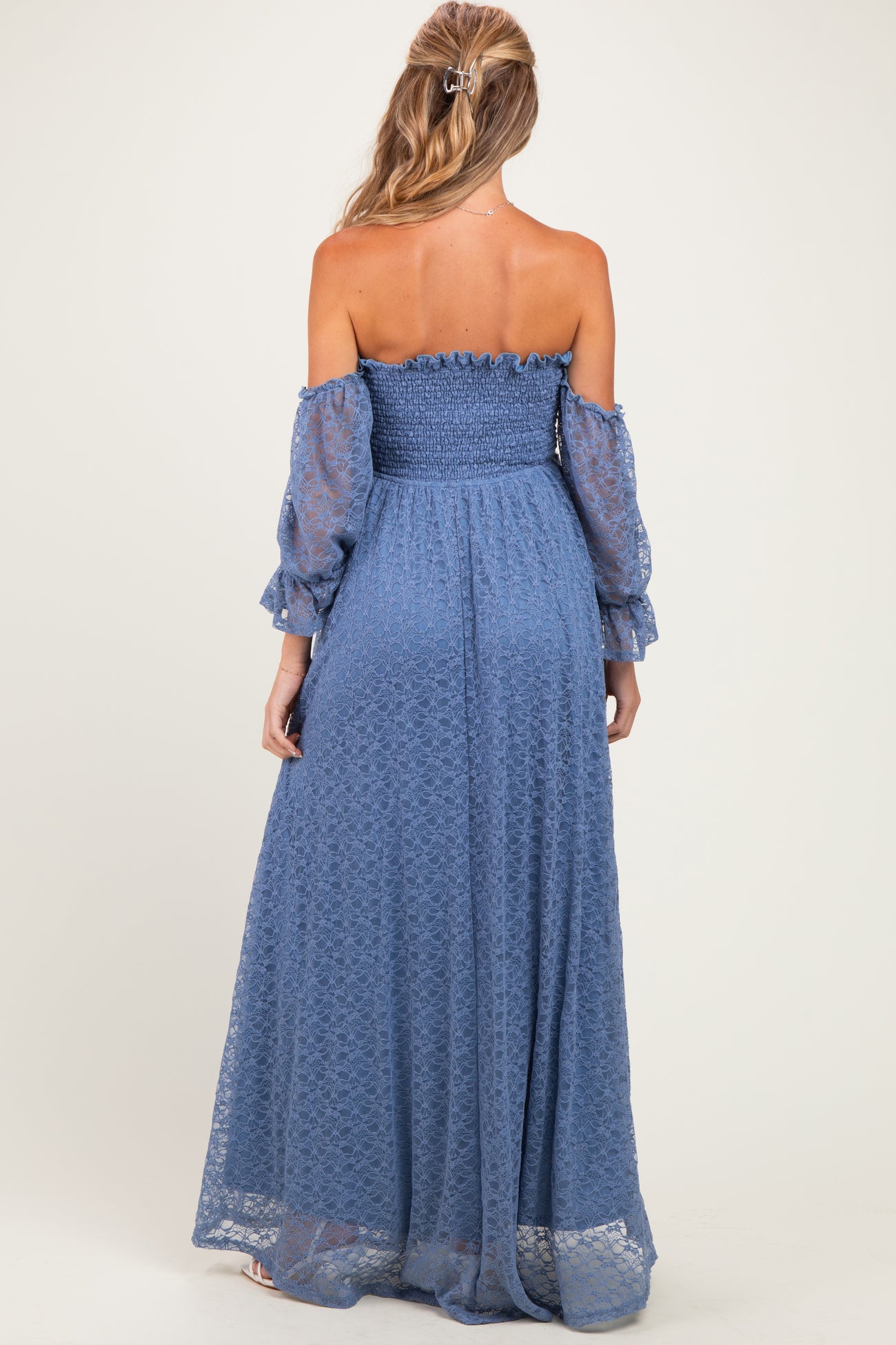 woman wearing a long off-the-shoulder blue maternity dress with smocked bodice and balloon sleeves, showing a baby bump