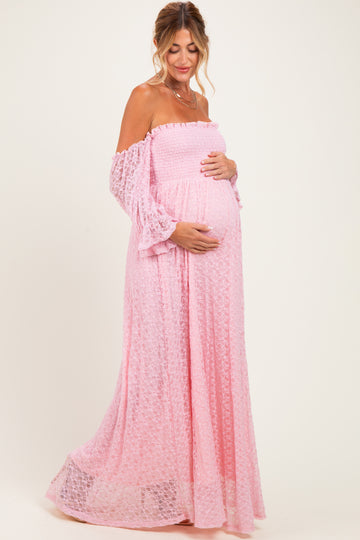woman wearing a pink off-the-shoulder maternity maxi dress and holding her baby bump