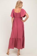 woman wearing a mauve maxi dress with flutter sleeves and a tiered hem, shown from the back