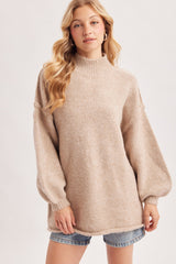 woman wearing a beige high-neck oversized sweater with balloon sleeves and styled with denim shorts