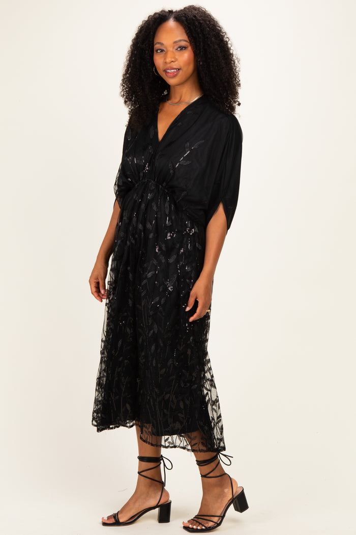 woman wearing a black floral lace midi dress with short sleeves and a fitted waist, paired with strappy black heels
