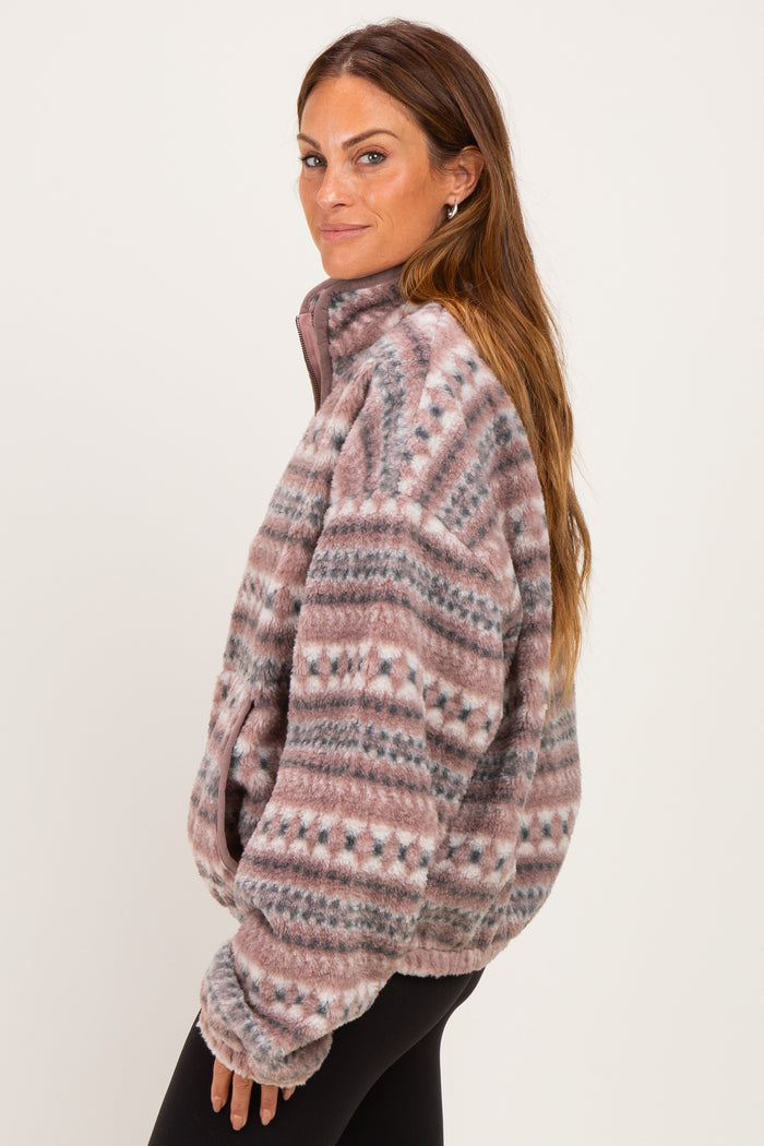 woman wearing a pink and gray patterned fleece jacket with a high collar and side pockets
