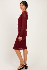 woman wearing a burgundy lace long sleeve midi dress with a fitted silhouette and side tie detail