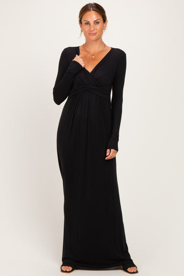 woman wearing a black long sleeve maxi dress with a twisted front detail and a relaxed fit