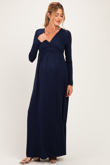 woman wearing a navy blue long sleeve maternity maxi dress with a wrap neckline and visible baby bump