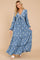 woman wearing a blue floral maxi dress with long sleeves and a tie detail at the neckline