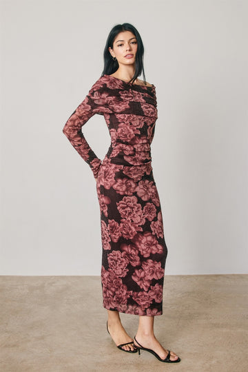woman wearing a burgundy floral long sleeve dress with a ruched design and a fitted silhouette