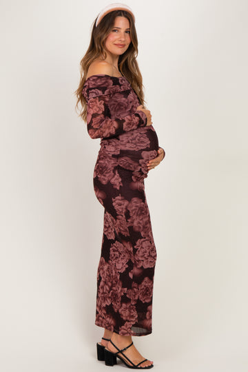woman wearing a burgundy floral off-the-shoulder maternity dress and holding her baby bump